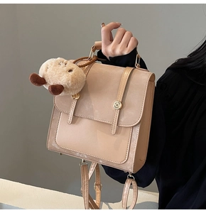 Detail view of beige matte leather backpack with gold buckles and cute capybara charm