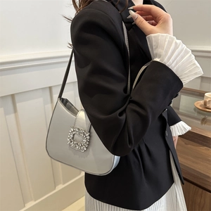 Sac baguette argenté avec boucle en cristal porté par un mannequin en décor élégant