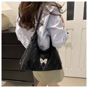 Détail du sac sous le bras vintage noir avec texture brillante et boucle papillon argentée
