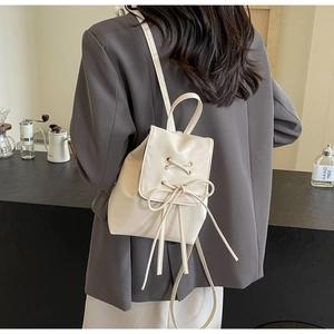 Chic cream white mini backpack with decorative drawstring tie shown on model's back