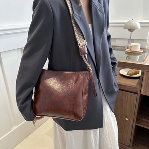 Vintage brown leather crossbody bucket bag with patterned wide strap and tassel detail