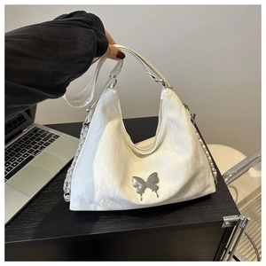 Gros plan sur le sac à bandoulière matelassé blanc avec breloque papillon et chaîne