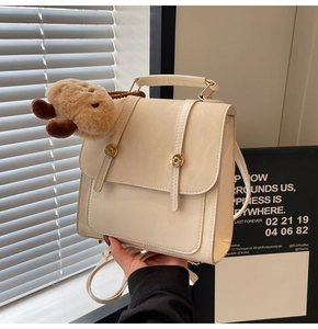 Detailed view of the retro cream backpack featuring golden buttons and a plush animal charm
