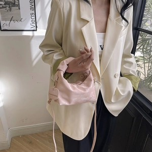 Pink minimalist handbag with knotted handle and shoulder strap shown in a lifestyle setting