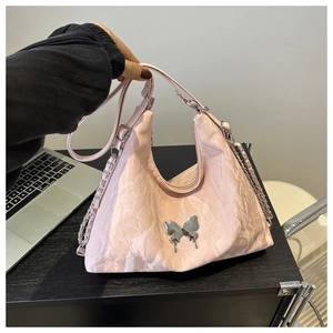 Détail du sac cabas rose clair avec texture plissée et ornement papillon en métal argenté