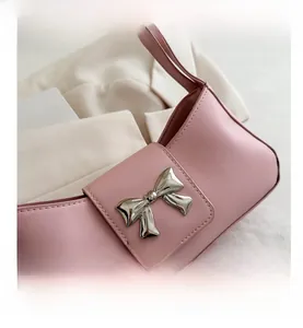 Detailed close-up of pink leather handbag with a silver metallic 3D bow on the flap cover