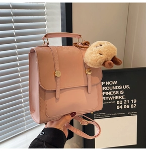 Detailed shot of pink PU leather mini backpack with gold buckles and plush charm