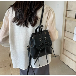 Rear view of black mini backpack with bow detail and adjustable straps on a model