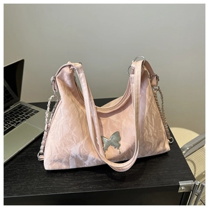 Détail du sac à main plissé rose avec boucle papillon argentée et bandoulière chaîne