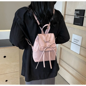 Close-up of pink PU leather backpack with decorative ribbon bow and lace-up detail