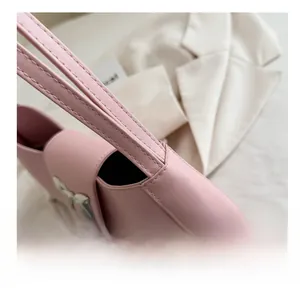 Detailed side view of pink faux leather handbag showing stitching and silver bow hardware
