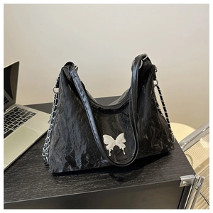 Détail du sac fourre-tout noir plissé avec breloque papillon argentée et bandoulière