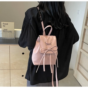 Detail of light pink mini backpack featuring decorative bow and elegant lacing design