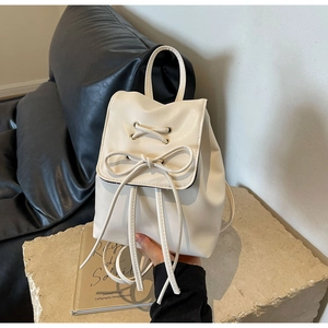 Detailed macro view of cream PU leather backpack with bow tie and metal eyelet accents