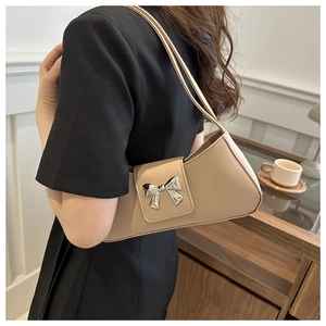 Detail view of beige leather underarm bag featuring a silver 3D bow metal buckle closure