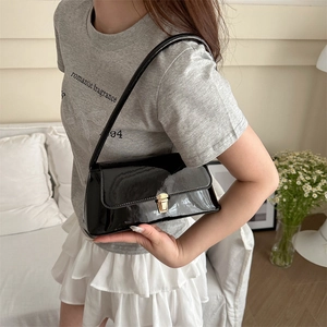 Sac bandoulière minimaliste en cuir verni noir avec fermoir métallique doré élégant