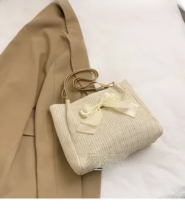 Détail d'un sac cabas en paille beige orné d'un grand nœud en satin crème sur tissage