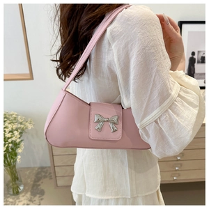 Detail view of pink baguette bag with silver bow buckle worn on the shoulder