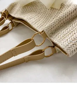 Détail du sac cabas en paille avec boucles en métal doré et poignées en cuir chic