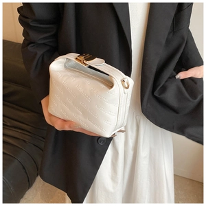 Détail du sac blanc en cuir avec motifs en relief et fermoirs dorés métalliques