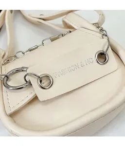 Detailansicht der silbernen Kette und FASHION & HC Schriftzug auf der beigen Ledertasche