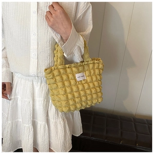 Detail shot of bright yellow bubble textured tote bag featuring Love Fashion label on handle