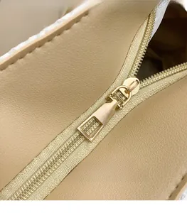 Détail de la fermeture éclair dorée et bordure tressée blanche du sac beige