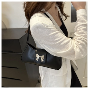 Detailed view of black matte leather underarm bag with silver metal bow buckle on a model