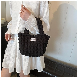 Detail of black popcorn texture shoulder bag with LOVE FASHION label on white dress