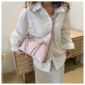 Close-up of a pink tote bag featuring bow accents and functional zipper pockets