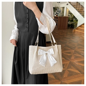 Détail du sac cabas en paille tissée avec un grand nœud en mousseline et boucles métal