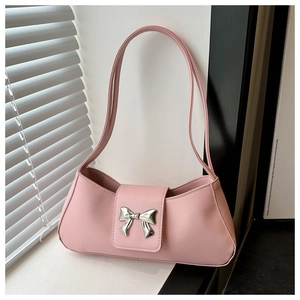 Detailed macro view of light pink shoulder bag with a metallic silver bow ornament