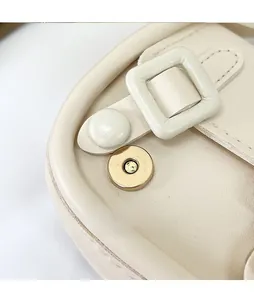 Détail de la boucle magnétique dorée et du grain de cuir sur le sac à main beige