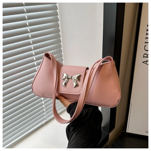 Close-up of pink leather shoulder bag featuring a silver metal bow buckle detail