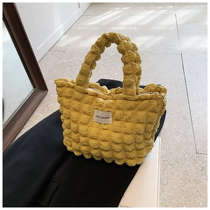 Close-up of bright yellow popcorn texture fabric tote bag with stylish white label detail