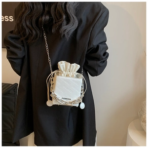 Close-up of a white bucket bag with drawstring closure and silver metallic chain straps