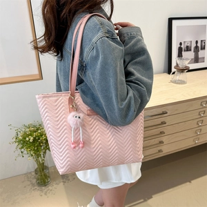 Borsa tote rosa trapuntata con motivo a onde e ciondolo pompon in ambiente domestico