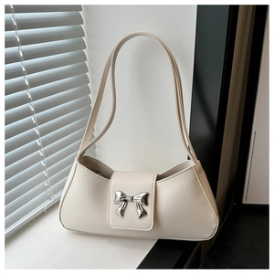 Detailed macro view of cream faux leather bag featuring a silver metal bow buckle accessory
