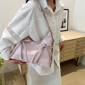 Pink minimalist tote hobo bag with bow decoration worn by a model in a cozy room