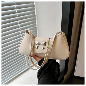 Detailed close-up of a cream-colored baguette bag with silver bow hardware and flap closure