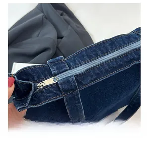 Close-up of the smooth silver metal zipper on the dark blue denim tote bag