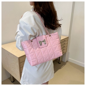 Detailed view of pink quilted shoulder bag featuring silver metal bow and chain strap