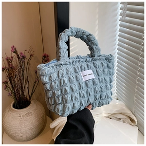 Detail of light blue bubble textured fabric bag with Love Fashion label and zipper