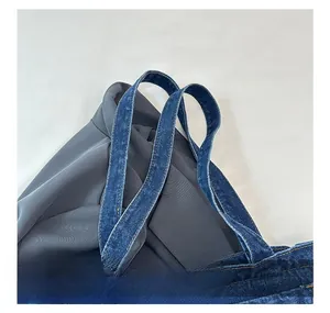 Detailed macro view of denim tote bag shoulder strap with reinforced double stitching