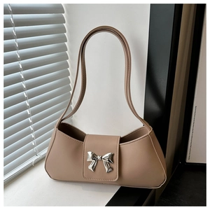 Detail of beige underarm bag with signature silver metal bow clasp and smooth texture