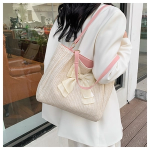 Détail du sac cabas en paille tissé avec nœud en soie crème et anses en cuir rose