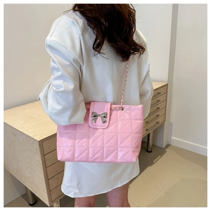 Close-up of pink quilted underarm bag with silver bow buckle worn by a model