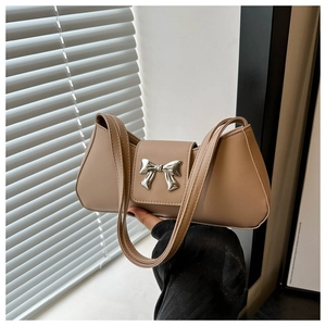 Detail of a beige underarm bag with a silver metal bow and slender double straps