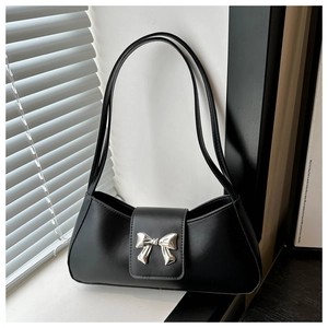 Detail of black leather underarm bag featuring a silver metal bow buckle and long shoulder straps