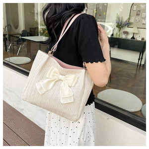 Détail du sac fourre-tout en paille tissée avec grand nœud en velours blanc et anses roses